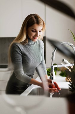 Çekici sarışın mutfakta yemek pişiriyor.