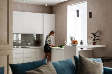 Çekici sarışın mutfakta yemek pişiriyor.