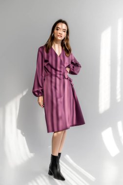 Beyaz arka planda mor kareli elbiseli çekici kahverengi saçlı kadın. Bir giyim kataloğu için fotoğraf çekinme