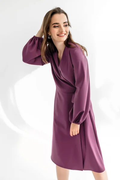 白い背景に紫色のチェッカードレスで魅力的な茶色の髪の女性 衣類カタログの写真撮影 — ストック写真