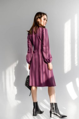 Beyaz arka planda mor kareli elbiseli çekici kahverengi saçlı kadın. Bir giyim kataloğu için fotoğraf çekinme