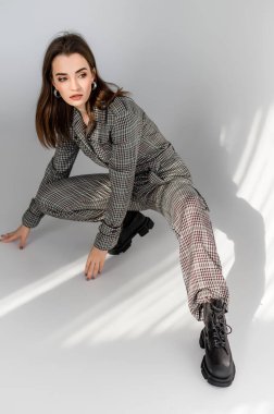 Beyaz arka planda damalı tulumlu çekici bir kız. Katalog, giyim dergisi