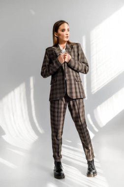 Beyaz arka planda damalı takım elbiseli çekici bir kız. Katalog, giyim dergisi