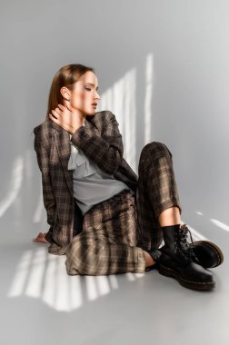 Beyaz arka planda damalı takım elbiseli çekici bir kız. Katalog, giyim dergisi