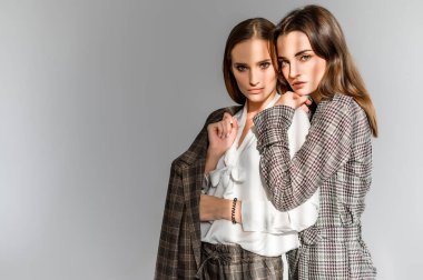 Pantolon giymiş iki kız ve beyaz bir arka planda çek önlüğü.