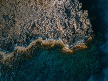 Dalgalar denizdeki kayaların üzerine düşüyor.