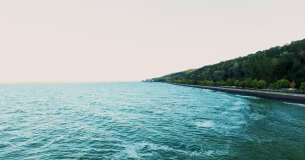 Embankment do oceano com areia e uma estrada na floresta, no pôr do sol tiro de um ponto alto, quadro de uma altura . — Vídeo de Stock