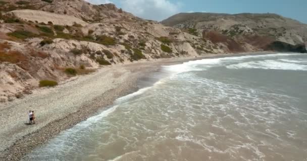 Vista aérea do casal em pé na borda do penhasco por mar — Vídeo de Stock