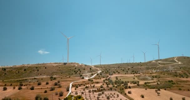 Volando alrededor de grandes turbinas eólicas en la planta de energía ecológica en Chipre. Drone vista de la enorme construcción de la estación en los prados en el campo de la isla . — Vídeos de Stock