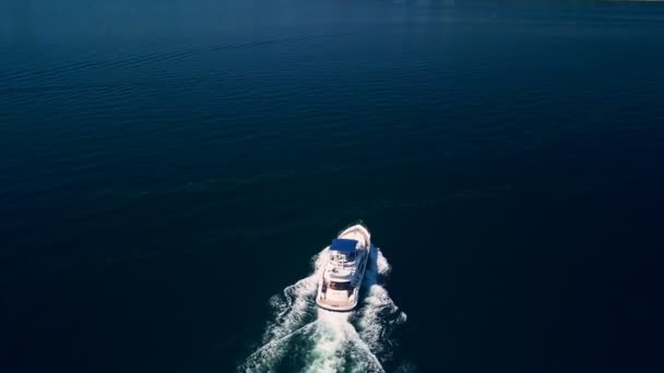 Top down drone tiro de um iate navegando através do oceano azul profundo com a luz ondulante embaixo — Vídeo de Stock