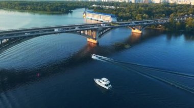 Denizin karşısındaki köprüdeki araba trafiğinin en alt görüntüsü. Havadan. Köprünün altından geçen çok sayıda çekici tekneden oluşan çekici konvoyu.