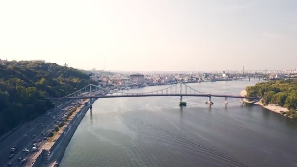 De dijk van de stad met uitzicht op de brug, auto 's rijden op de weg, een drone raakte de brug en klom naar de hemel — Stockvideo