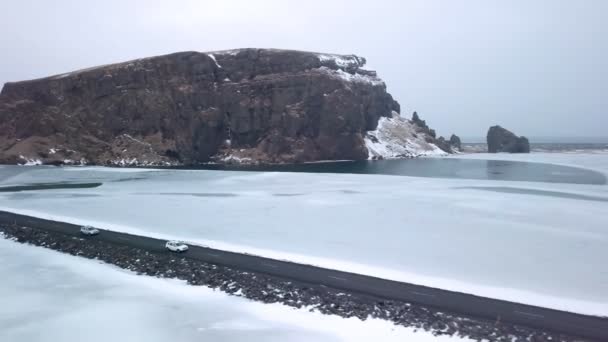 Två bilar kör längs en vacker slingrande väg på en vulkanisk landskap på Island. En drönare flyger bakom en bil.. — Stockvideo