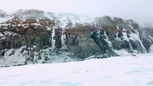 İzlanda 'da dağ insansız hava aracı vuruldu, insanlar karda dağlarda yürüyor. — Stok video