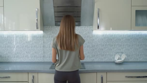 Молодая девушка на легкой кухне пробует приготовленный суп — стоковое видео