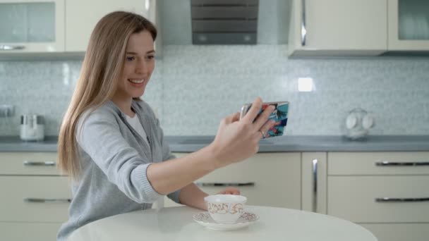 Selfie pessoa feliz. Mulher surfando mídias sociais em smartphones em casa. Menina bonita com cabelo rosa leva uma selfie e não percebe fogo na cozinha . — Vídeo de Stock