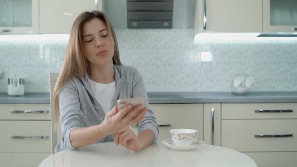 Belle fille parlant sur le téléphone mobile dans la cuisine à la maison. — Video