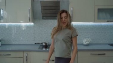 Mutlu bir kızın enerjik dansı. Genç ve güzel bir kadın mutfakta dans edip müzik dinliyor. Güzel bir kadın müzik dinliyor.