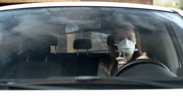 Το κορίτσι χειρίζεται τα χέρια και το αυτοκίνητο με ένα αντισηπτικό κάθεται στο αυτοκίνητο, θέα μέσα από το γυαλί — Αρχείο Βίντεο