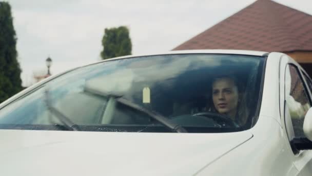 Κορίτσι κάθεται σε ένα αυτοκίνητο και ενεργοποιήστε τους υαλοκαθαριστήρες — Αρχείο Βίντεο