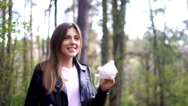 Linda chica se quita una máscara médica de su cara e inhala profundamente el aire en el bosque — Vídeo de stock