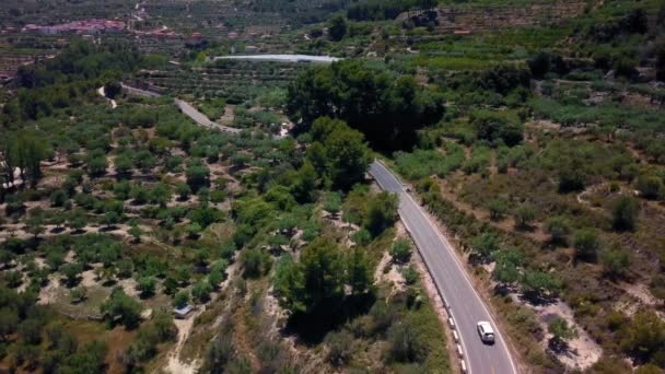 El coche viaja por la carretera en las tierras altas. Drone disparando desde la parte superior y lateral. Vista de la carretera, coche negro, árboles de coníferas, hierba. Coche Premium . — Vídeos de Stock