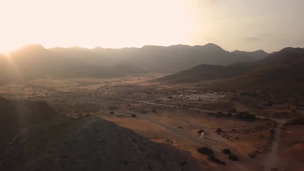 Pemandangan udara tebing batu dan pantai, air laut saat matahari terbenam. Terbang di atas gunung — Stok Video