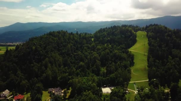 Panela do círculo aéreo da pista de esqui de Kope e um lago em densa floresta de pinheiros na Eslovénia — Vídeo de Stock