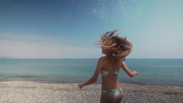 Menina se movendo em torno de si mesma em um maiô no mar — Vídeo de Stock
