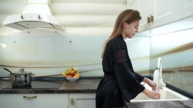 Güzel kadın mutfakta bulaşık yıkar.
