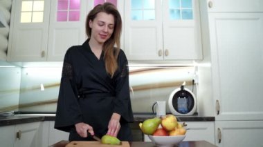 Güzel bir kadın mutfakta armut keser.