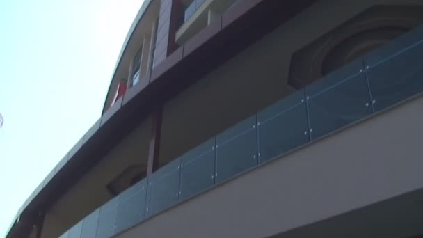Modernes neues Hotel vor blauem Himmel, neben einem Pfau stehend — Stockvideo