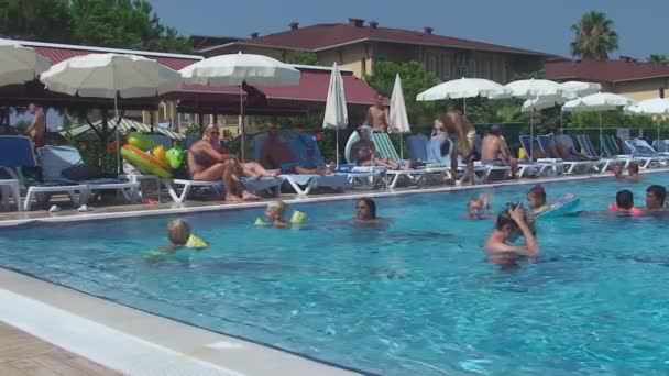土耳其安塔利亚，2015 年 8 月 20 日︰ 人在游泳池里游泳，在沙滩上晒日光浴 — 图库视频影像