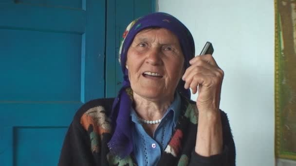 The elderly woman in a colorful headscarf talking on the phone — Stock Video