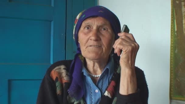 The elderly woman in a colorful headscarf talking on the phone — Stock Video