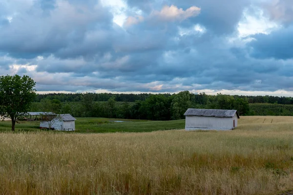 Granero blanco en un campo con cielo y nubes en el fondo — Foto de Stock