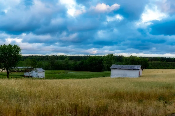 Granero blanco en un campo con cielo y nubes en el fondo — Foto de Stock