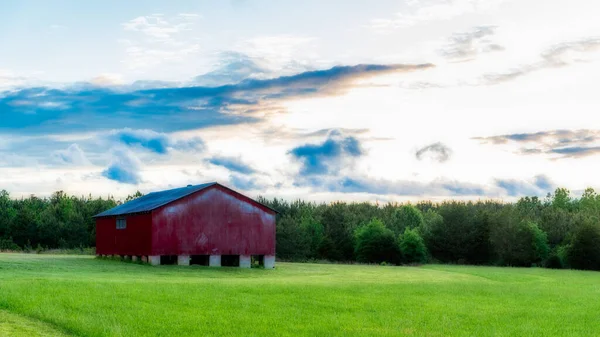 Czerwona stodoła na polu z niebem i chmurami w tle — Zdjęcie stockowe