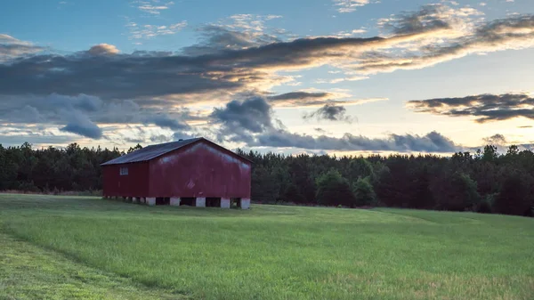 Granero rojo en un campo con cielo y nubes en el fondo — Foto de Stock