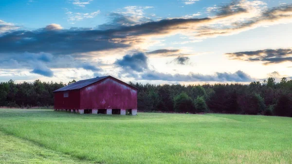 Granero rojo en un campo con cielo y nubes en el fondo — Foto de Stock