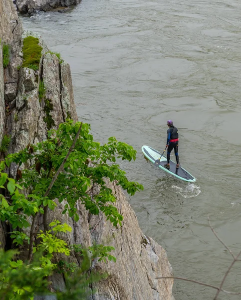 man standing on kayak and paddling