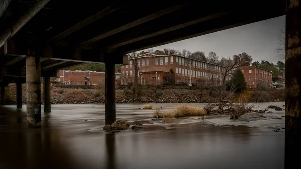 Edificio industrial enmarcado por un puente que atraviesa el río Haw — Foto de Stock