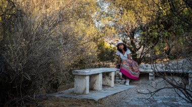 Atina 'da beyaz tişörtlü, beyaz şapkalı Asyalı bir kadın oturuyor. 