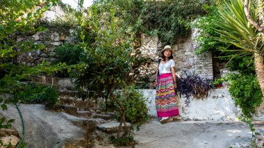 Atina 'da beyaz şapkalı ve saronlu beyaz tişörtlü Asyalı kadın.