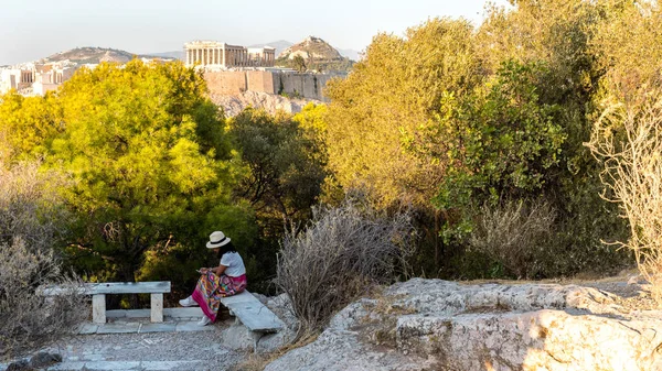 在雅典，身穿白色T恤、头戴白帽的亚洲女人坐在那里 — 图库照片