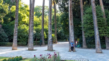 Beyaz fötr şapkalı ve mavi kravatlı Asyalı kadın ayakta dururken öldü.