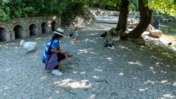 Mujer asiática con sombrero y gafas de sol de rodillas delante de pato — Foto de Stock