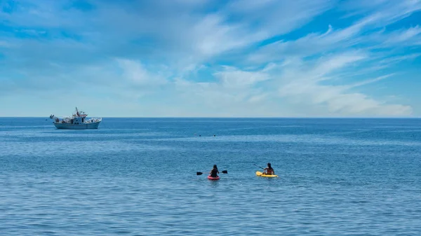 Dos Kayakers con barco de pesca griego en ancla en el fondo — Foto de Stock