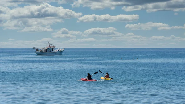 Dos Kayakers con barco de pesca griego en ancla en el fondo — Foto de Stock
