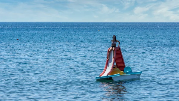 Adolescente en traje de baño sentado en paddleboat con diapositiva — Foto de Stock